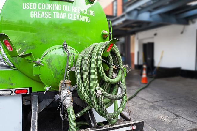 a grease trap being pumped by a sanitation technician in Elmhurst